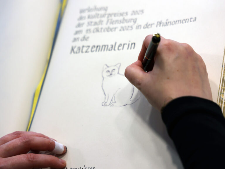 Flensburger Katzenmalerin zeichnet ins Goldene Buch der Stadt